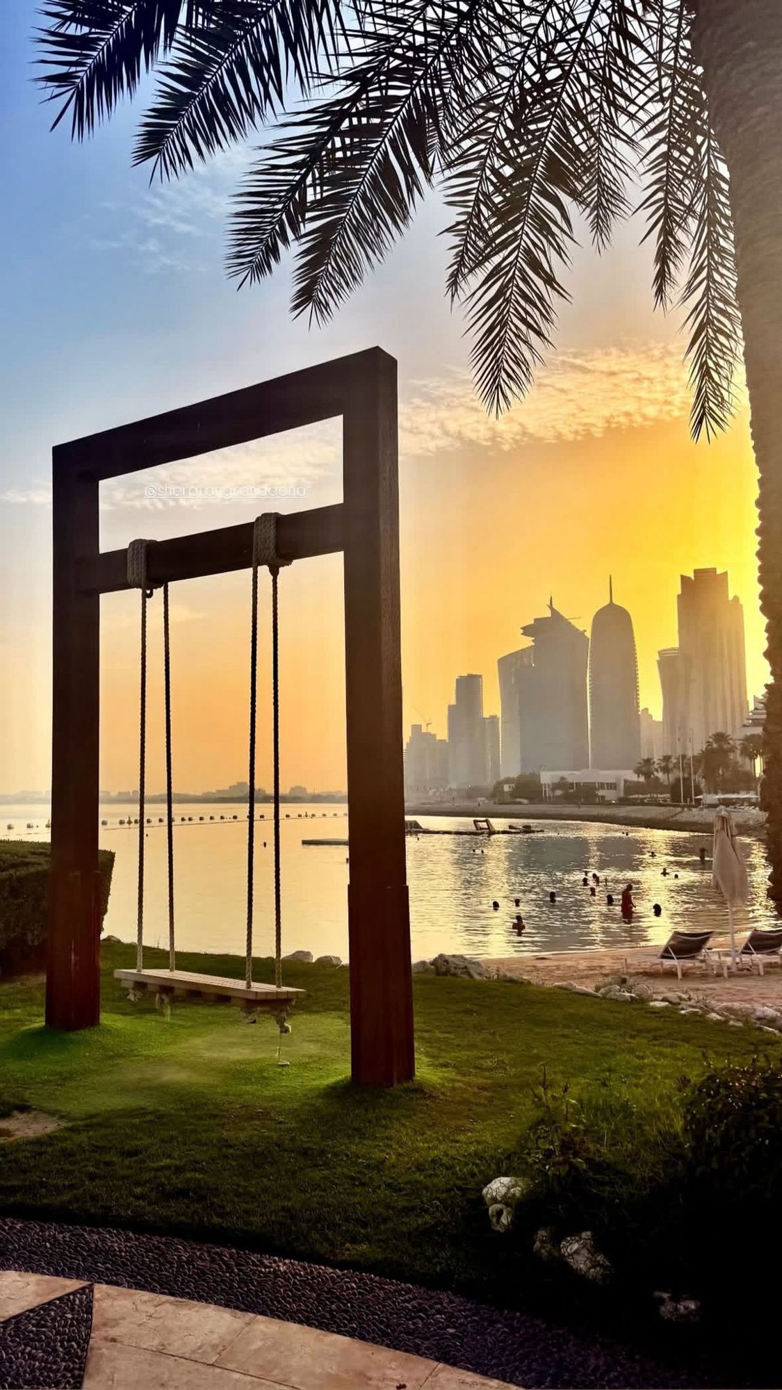 Beach swing at sunset with the Doha skyline